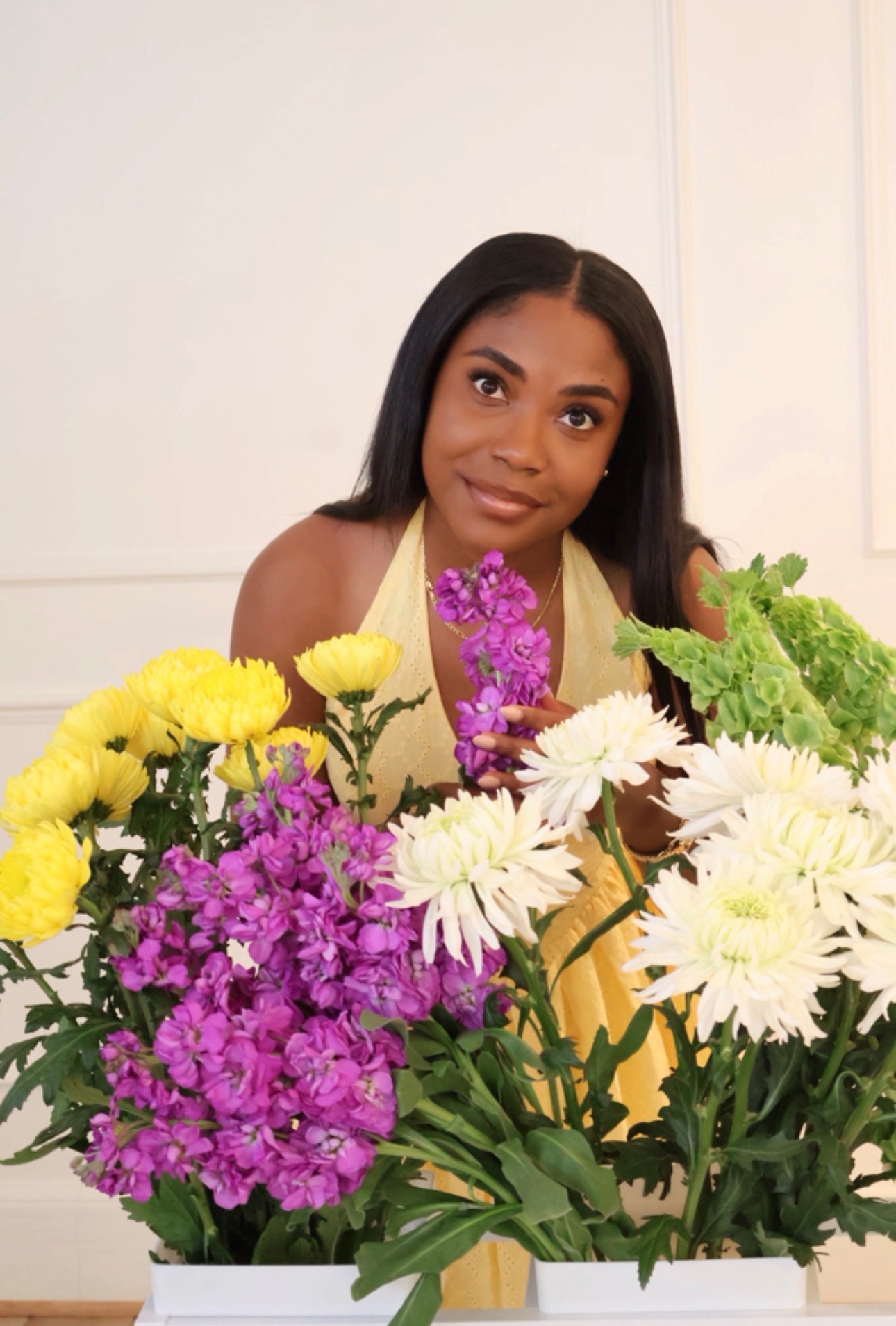 A woman holding a purple stem among bright yellow and white flowers