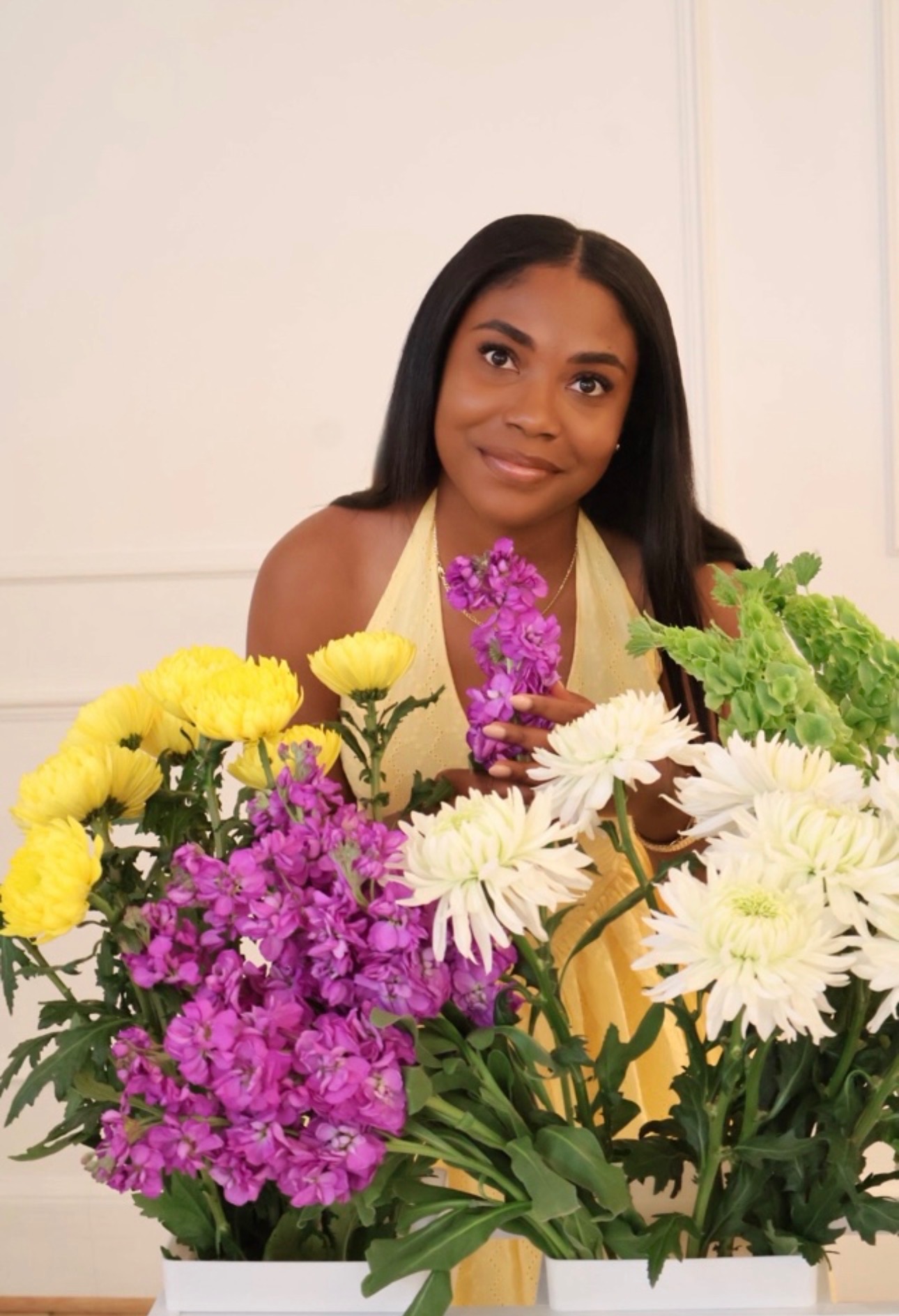 A woman smiling among fresh flowers and green foliage